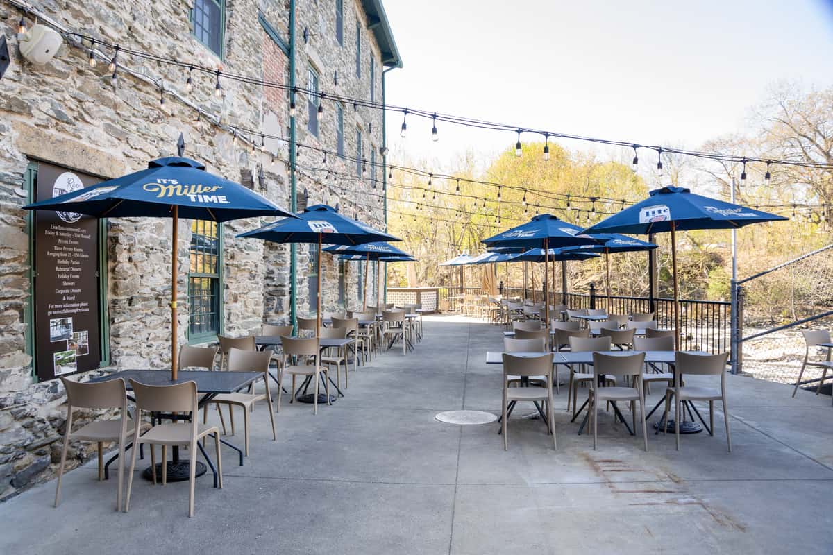 stone courtyard patio with blue umbrellas and outdoor restaurant tables in a scenic dining area
