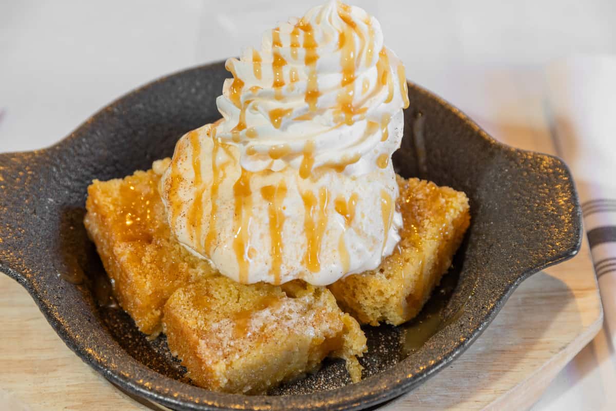sweet cornbread sundae with whipped topping and caramel sauce served in a skillet dish