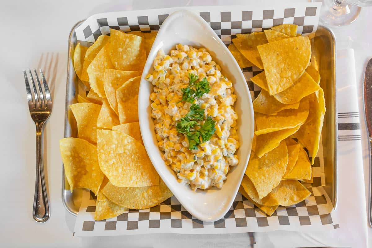 creamy street corn dip with tortilla chips served in a basket-style appetizer tray