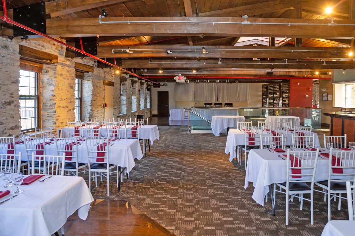 large event space with rustic wood ceilings, banquet tables, and natural light from surrounding windows