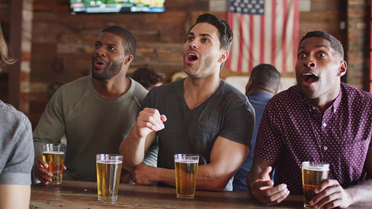  friends celebrating whilst watching a sports game at a bar