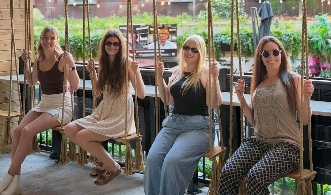 Four women swinging on the swings on the patio at the Rabbit Hole