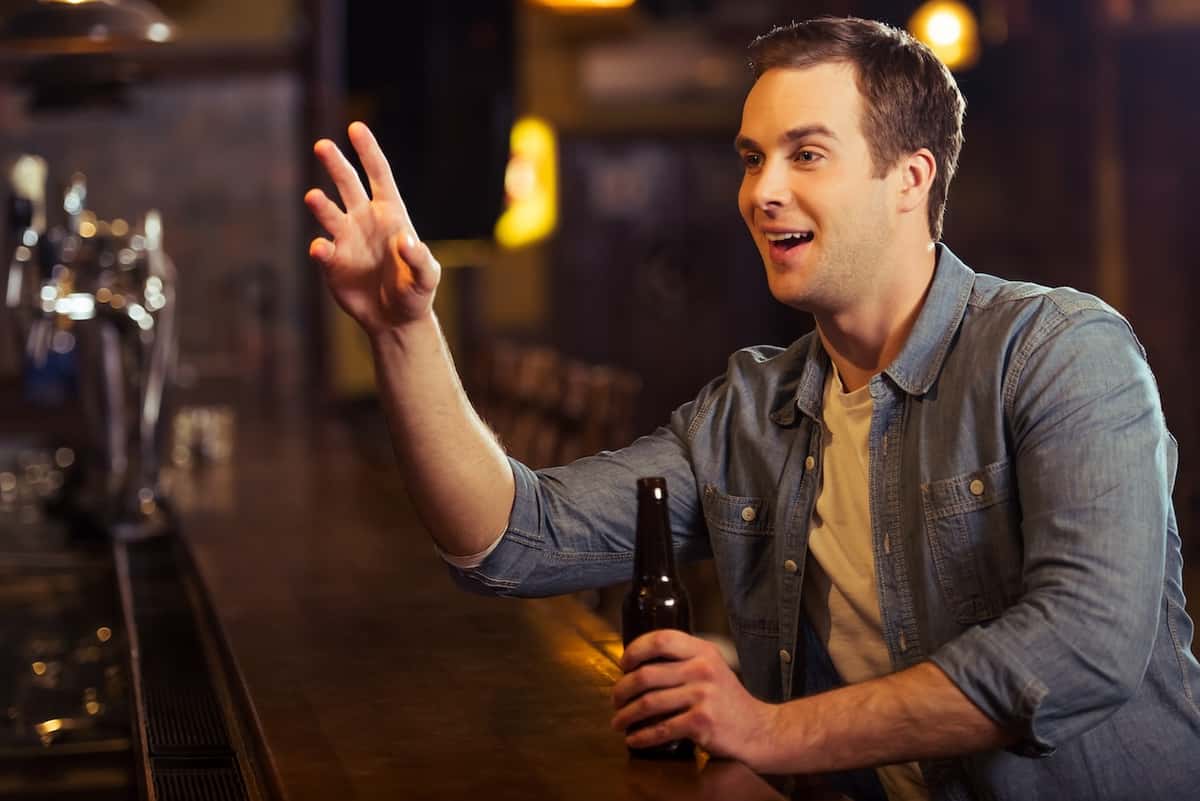 gentleman ordering a drink at the bar waving the bartender down respectfully