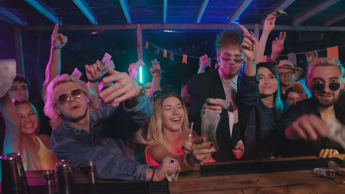 rowdy crowd at a bar ordering drinks chaotially, waving money in the air and shouting