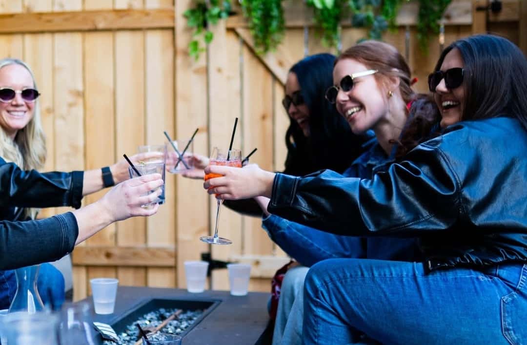 A group of girl friends enjoying drinks and laughing on the patio at the Rabbit Hole