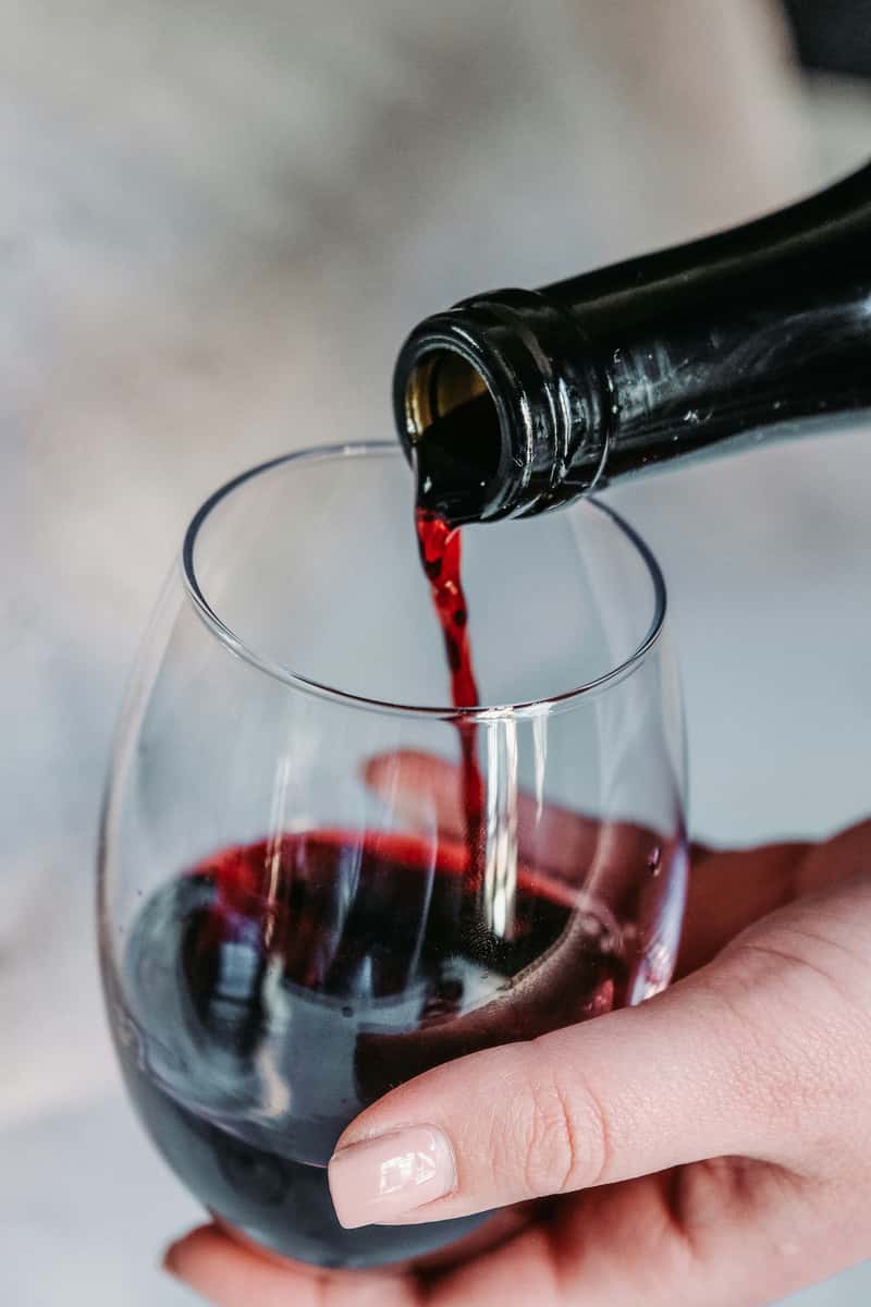 person pouring glass of red wine
