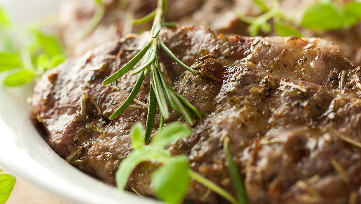 Juicy grilled lamb chops seasoned with herbs and garnished with fresh rosemary and oregano.