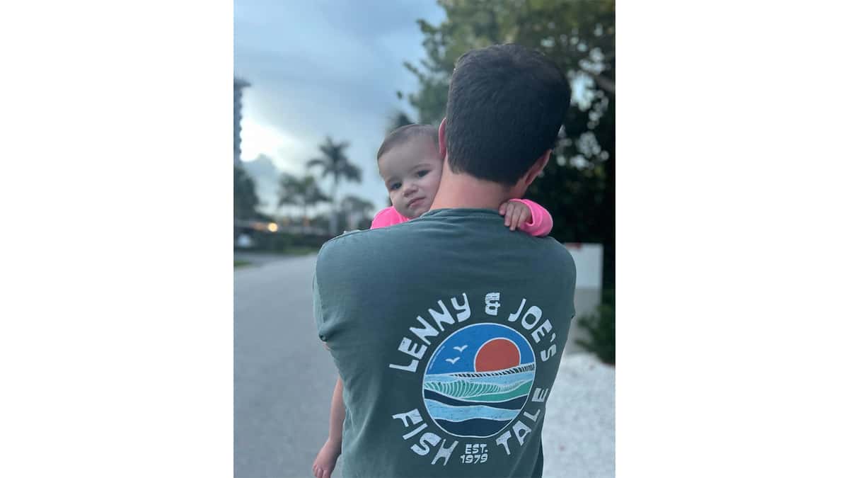Dad wearing Fish Tale Shirt holding his young daughter
