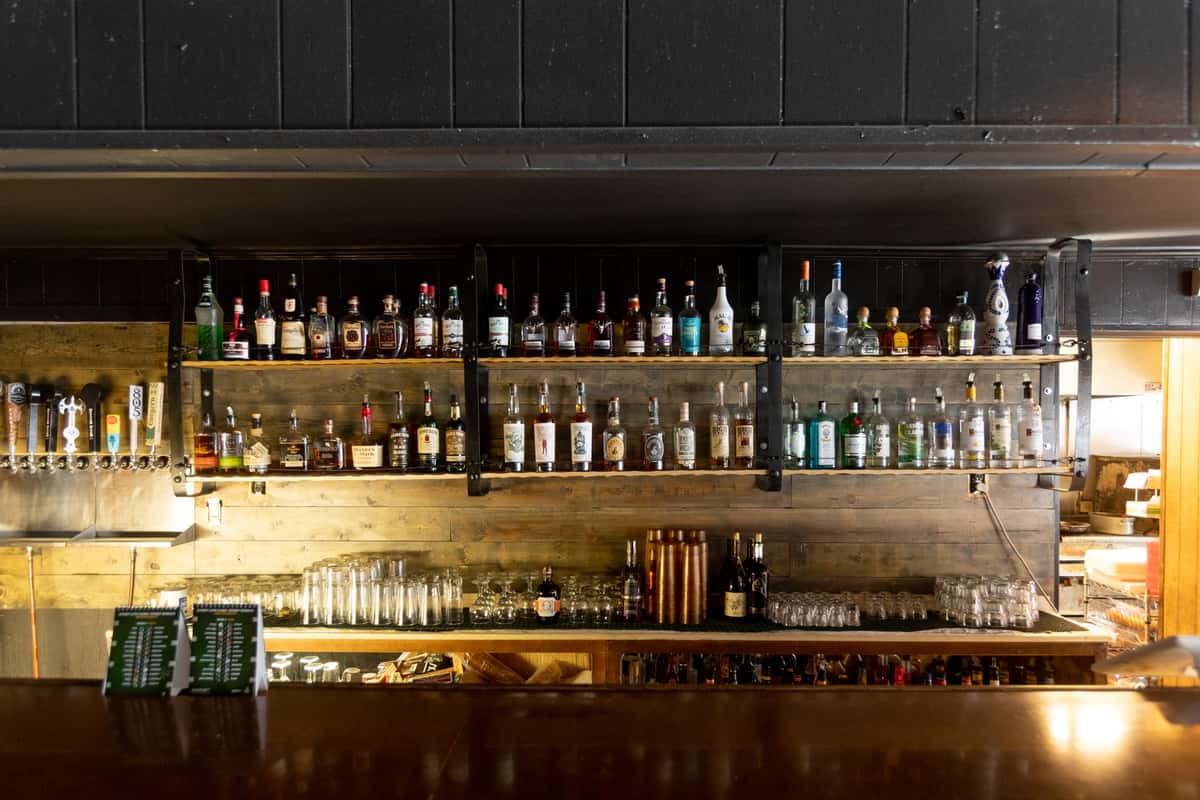 Image of a bar with menus on the wall and liquor collection display