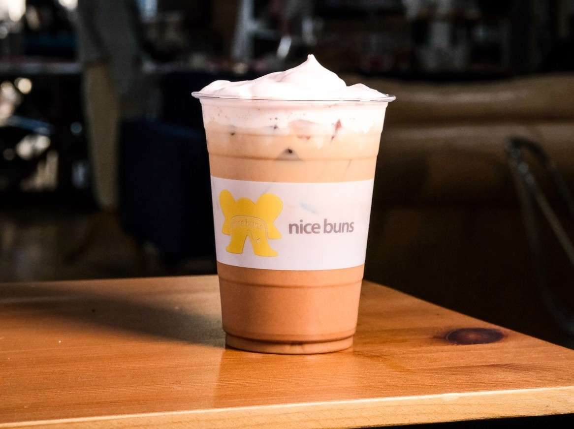 Creamy iced chocolate drink topped with whipped cream in a Bread & Butter Bakery and Cafe cup, perfect for a sweet café treat.