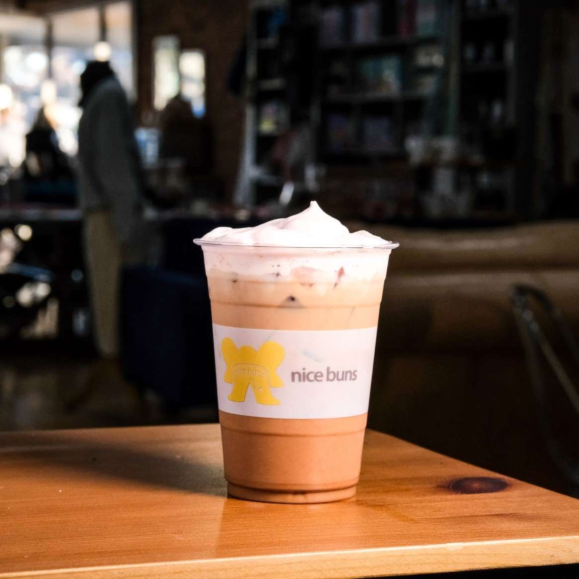 Creamy iced chocolate drink topped with whipped cream in a Bread & Butter Bakery and Cafe cup, perfect for a sweet café treat.