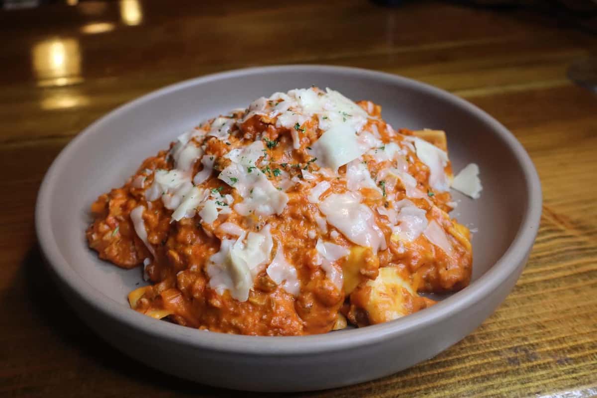 Hearty baked pasta topped with rich meat sauce and melted mozzarella, finished with shaved Parmesan in a cozy pub setting.