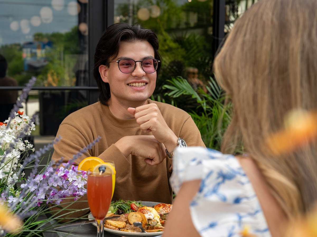 Friends enjoying drinks and conversation at an outdoor restaurant patio.