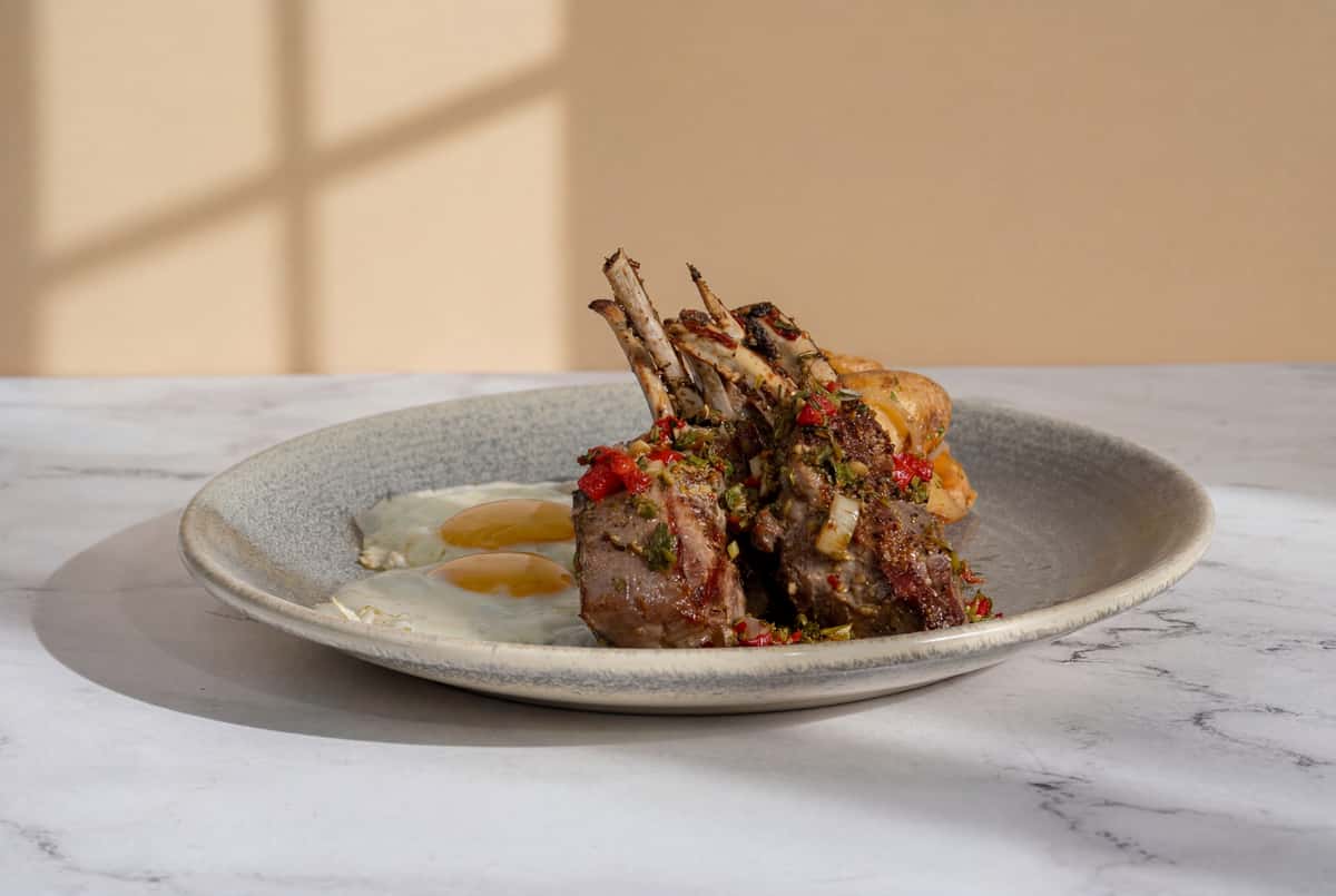 Grilled lamb chops plated with roasted vegetables and elegant herb garnish.
