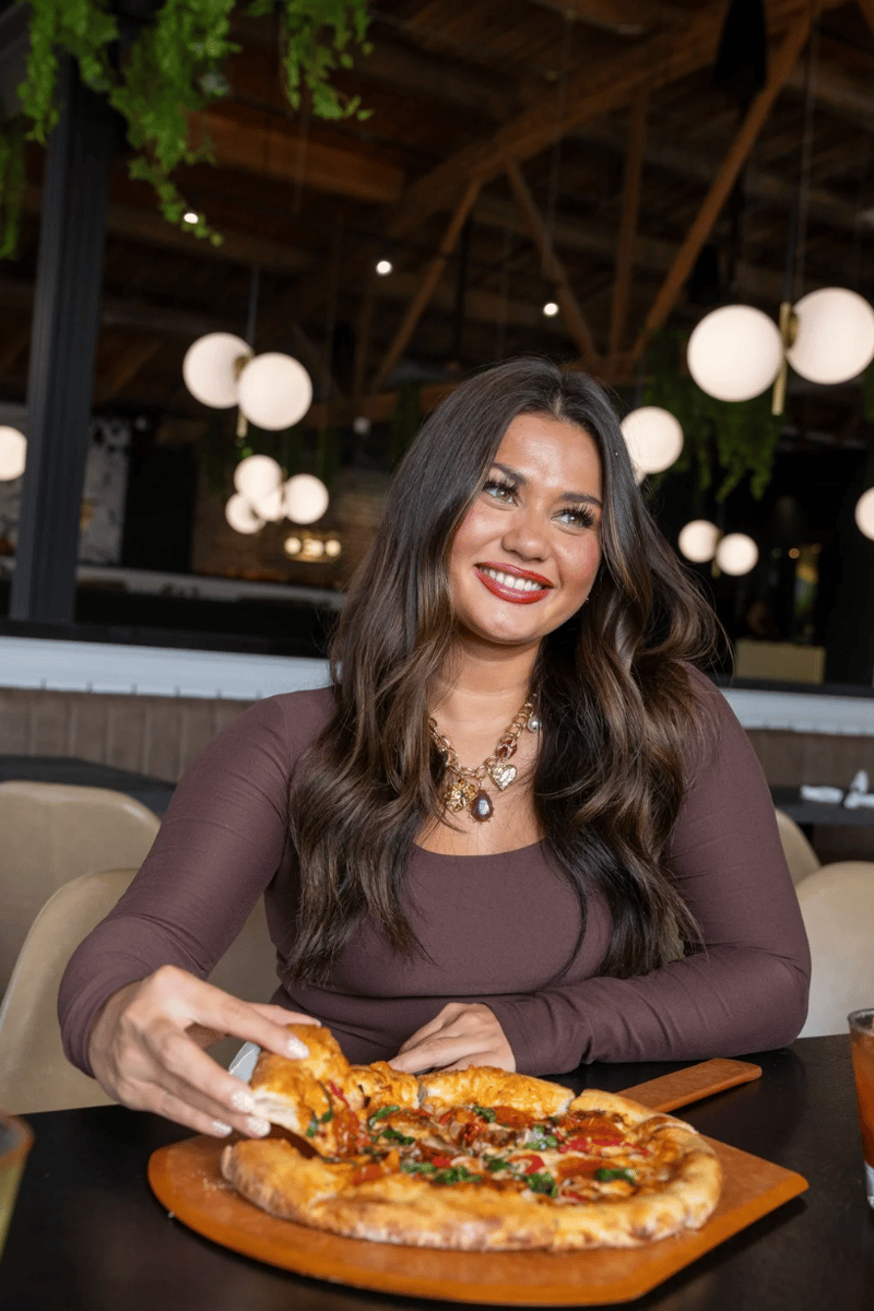 Woman pulling a slice of pizza from a tray