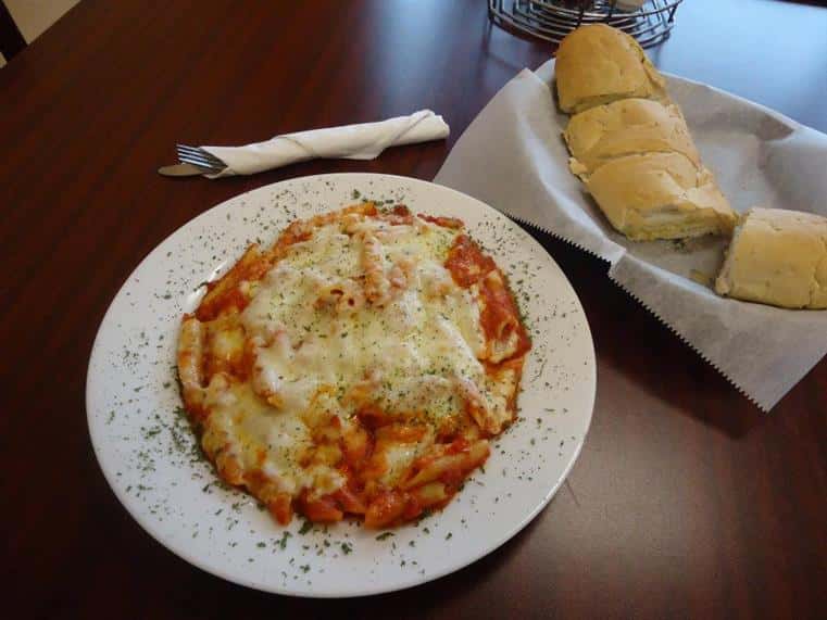 dish of baked ziti with melted cheese, basket of bread