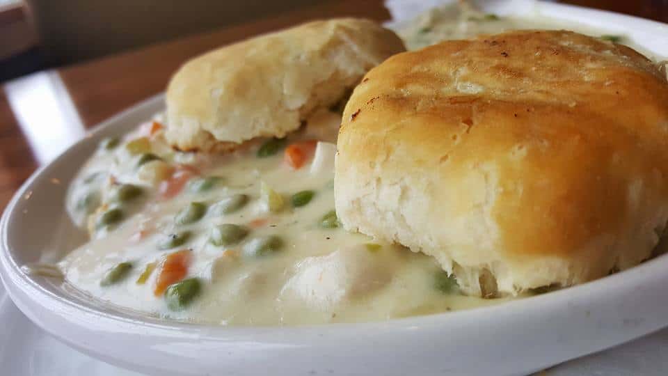 Chicken pot pie with biscuits in a white bowl.