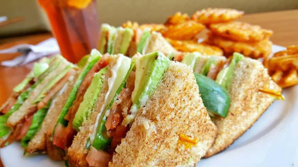 Turkey club sandwich with lettuce, bacon and mayo with waffle fries and a pickle spear