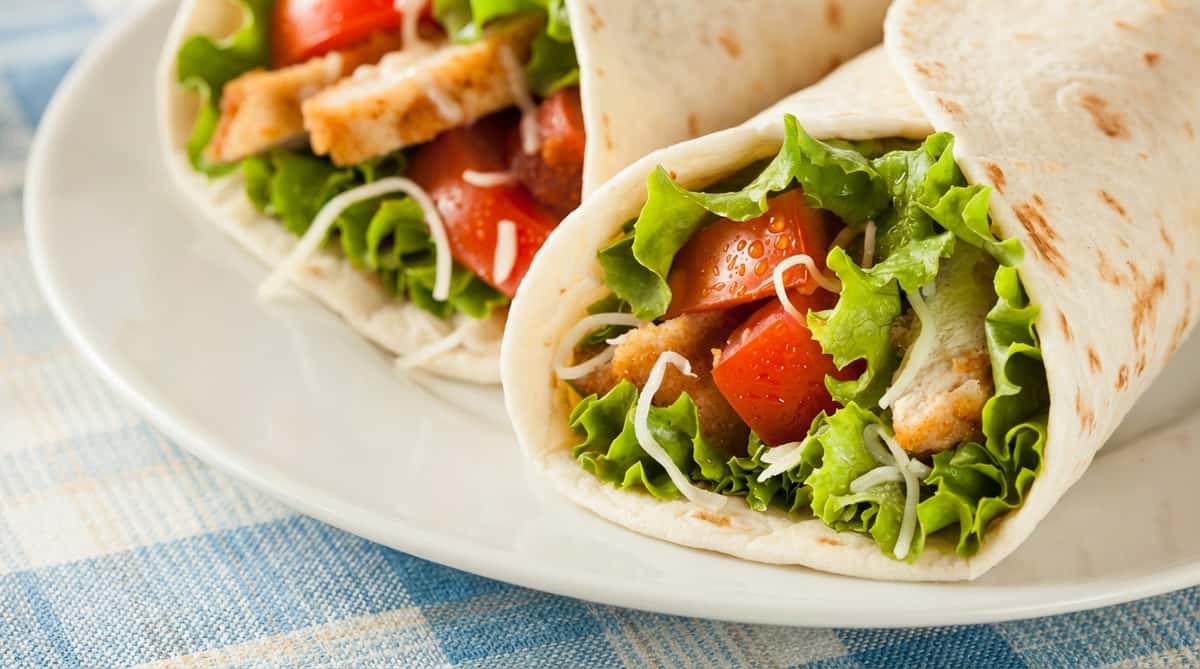 Tony's Donuts logo over a chicken wrap with lettuce, tomatoes, and shredded cheese.