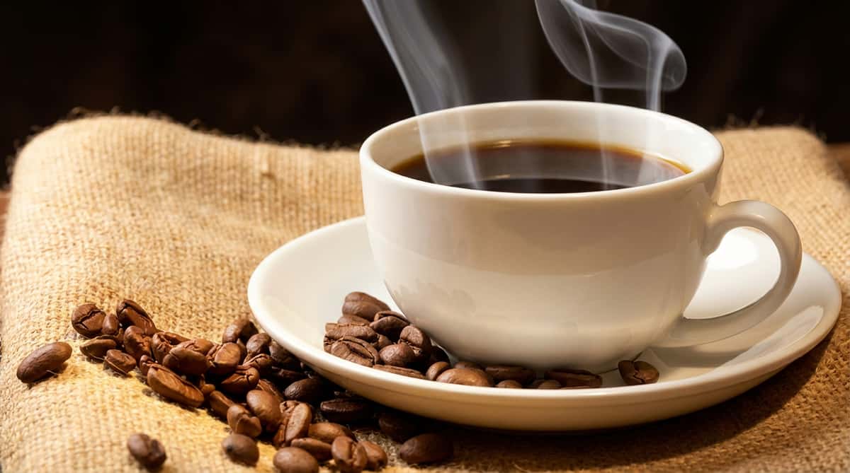 Steaming cup of coffee with coffee beans on a burlap cloth, with "Welcome to Tony's Donuts" text.
