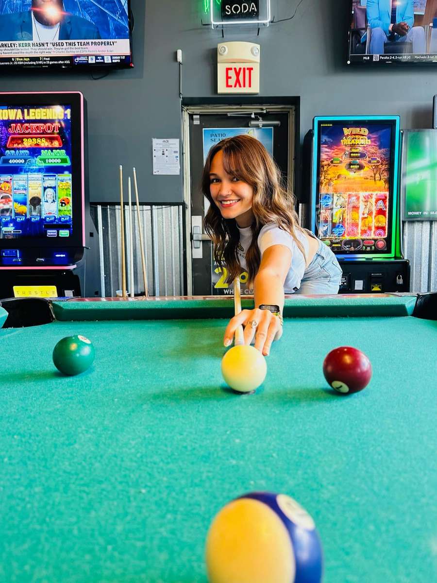 A girl shooting a shot in pool.