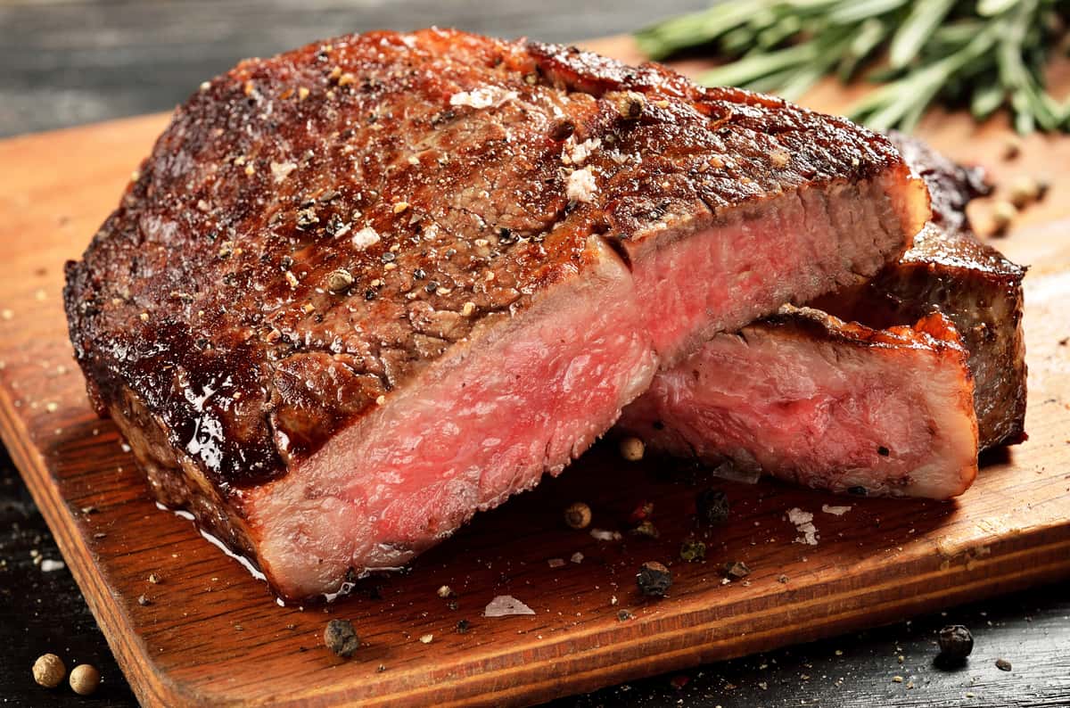 Sliced medium rare steak resting on a wooden cutting board