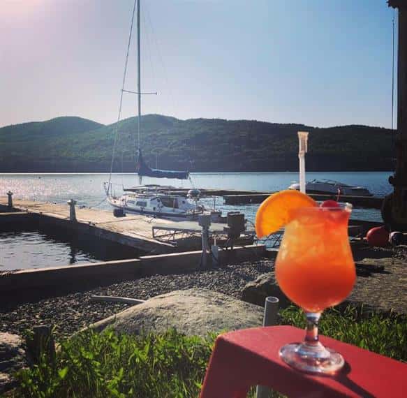 fruity cocktail on the arm of a lawn chair overlooking boats and Lake Champlain