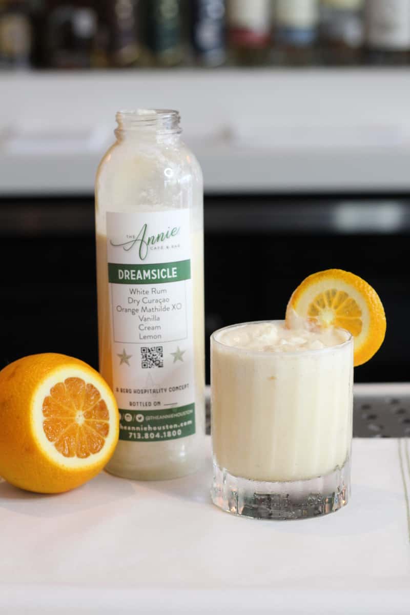 a close up of a bottle and a glass of orange juice