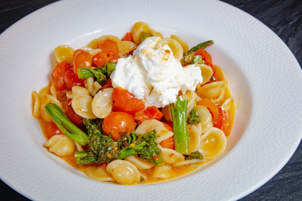 Creamy burrata served over house-made pasta with asparagus, cherry tomatoes, and rich tomato sauce at Dulivia Ristorante Italiano in Springdale, Utah.