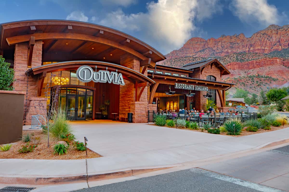 Exterior of Dulivia Ristorante Italiano in Springdale, Utah, featuring elegant architecture, red rock mountain views, and an inviting entrance near Zion National Park.