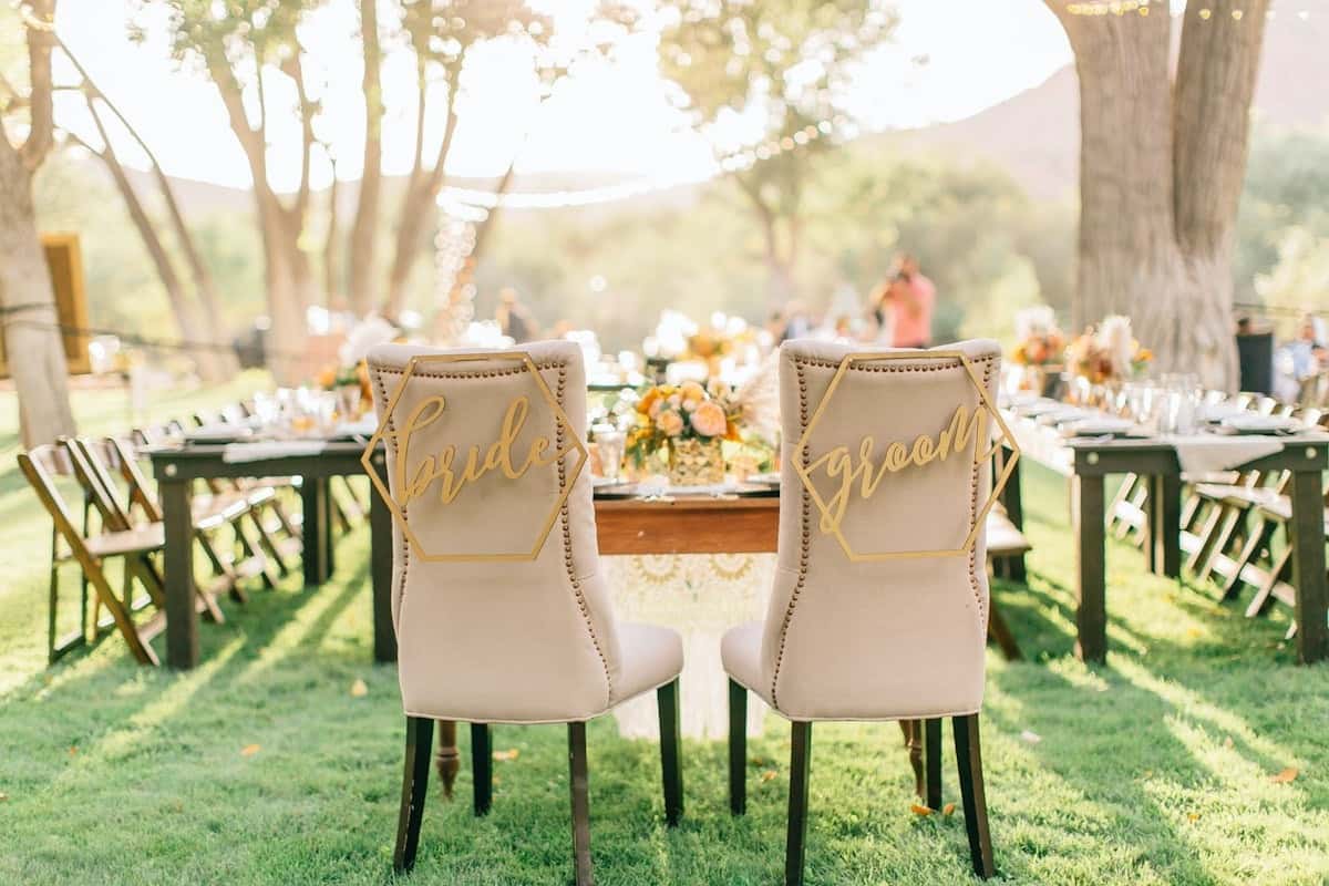 Outdoor wedding reception with bride and groom chairs, elegant table settings, and scenic garden venue for catered events and private celebrations.