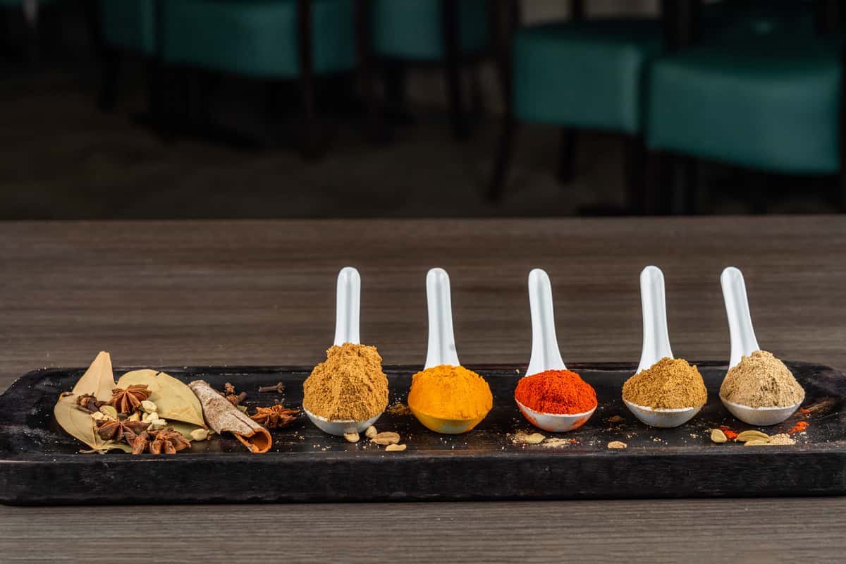Four spoons with seasoning on them in a row