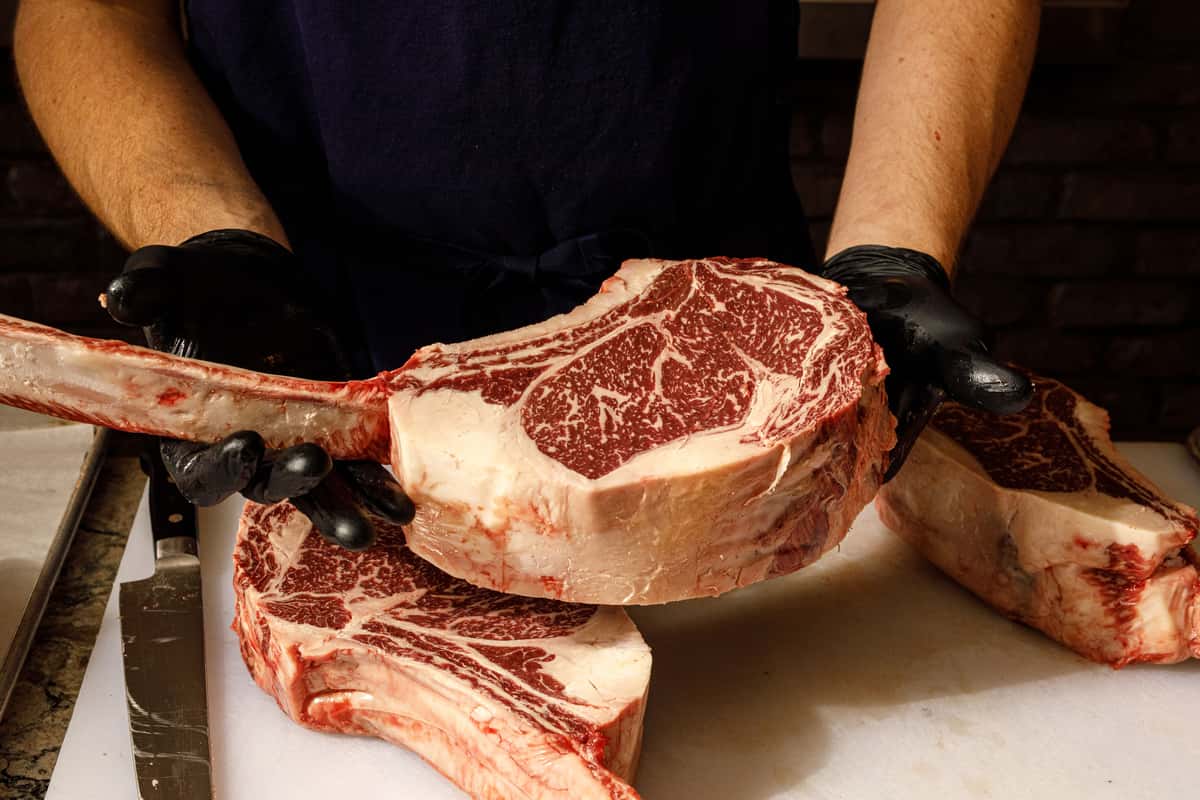 Chef holding house cut wagyu tomahawk steaks