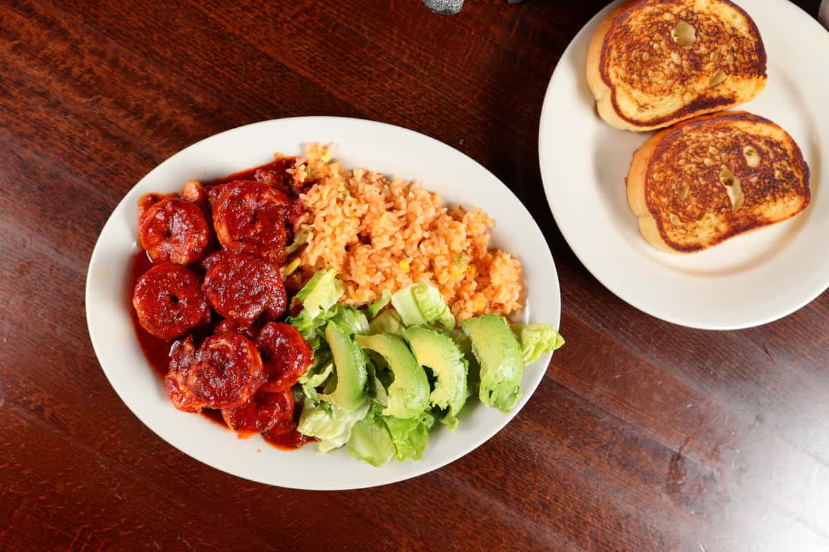 Top-view picture of a Mexican dish of rice, avocado on a white plate.