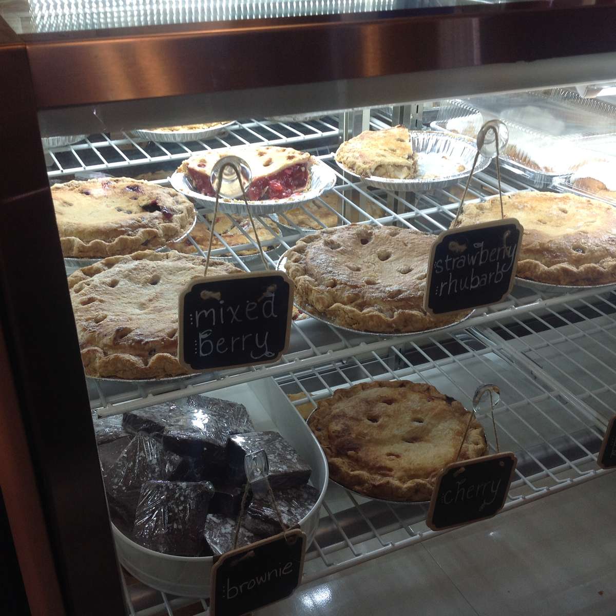 Assortment of golden brown pies and dark brownies in a display case at The Sunflower Bakery Café.