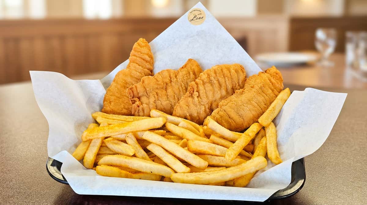 Four golden-brown chicken strips and seasoned french fries in a basket lined with white paper