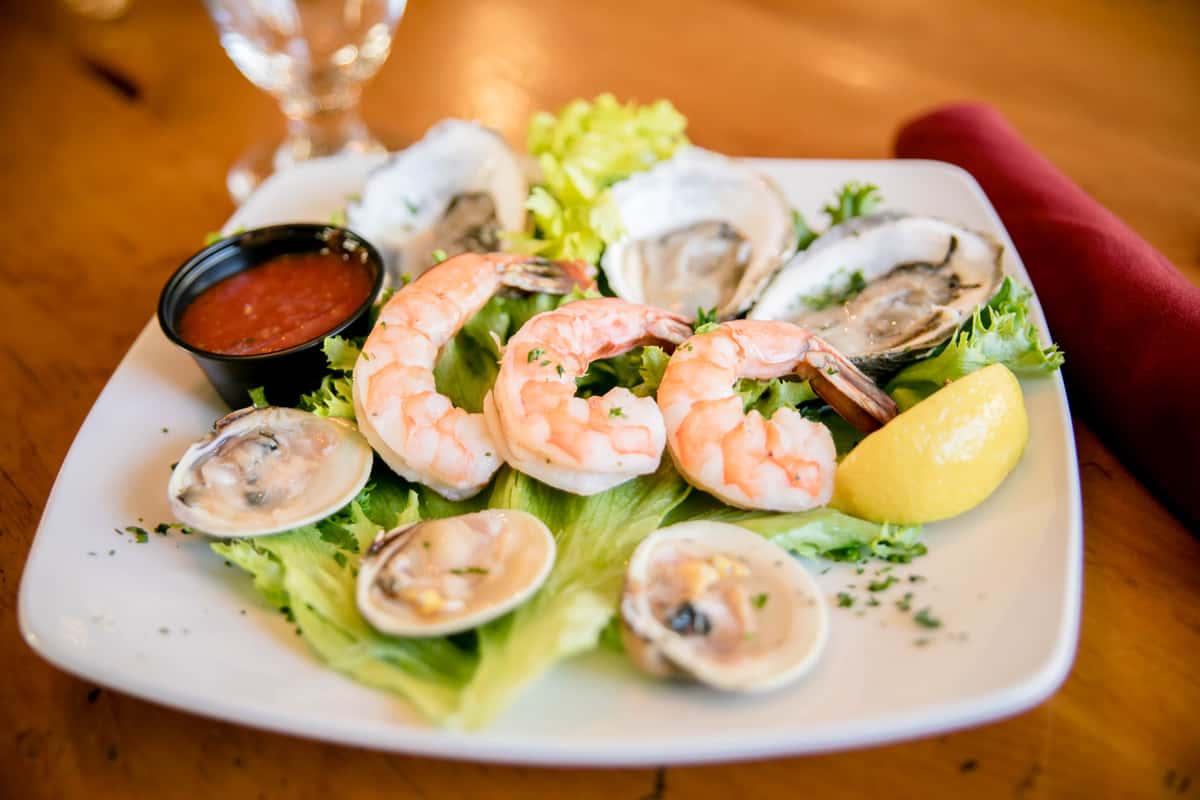 Chilled shrimp cocktail served with clams, lemon, and cocktail sauce.