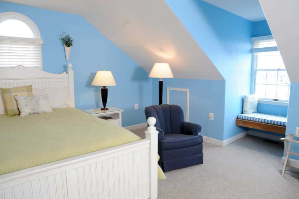 Bedroom with light blue painted walls, a night stand with lamp and a small blue side chair