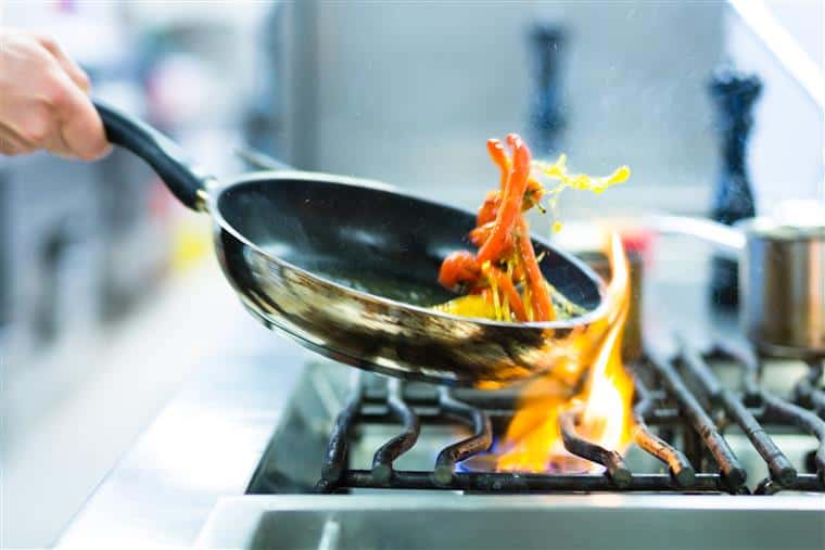 cooking food in a pan over a lit stove