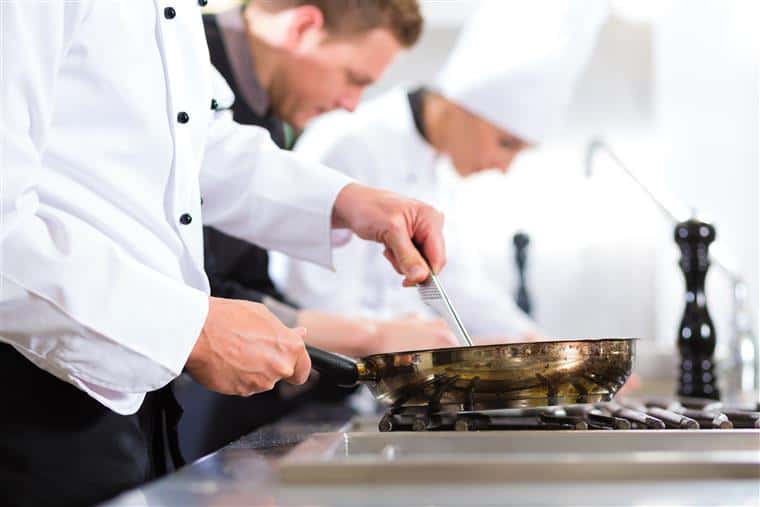 chefs cooking with pans in a kitchen
