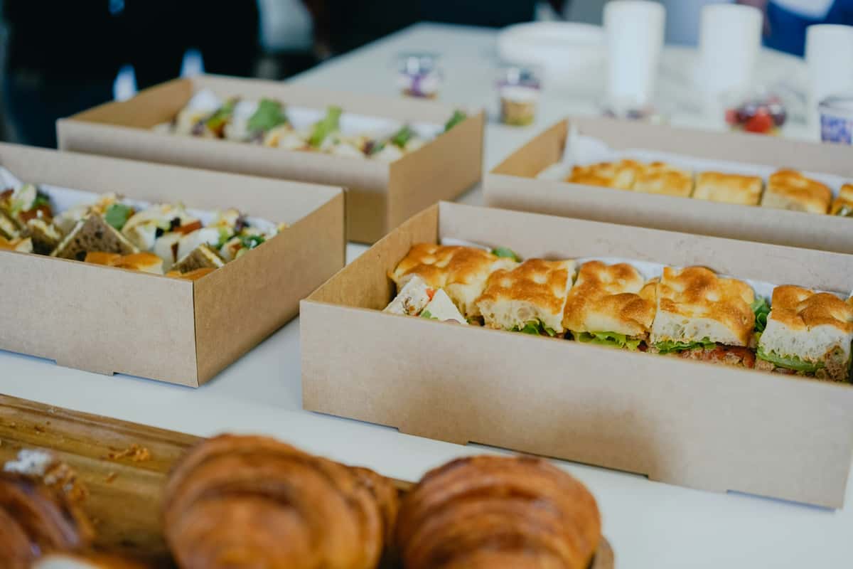 Gourmet boxed lunches with assorted artisan sandwiches in kraft catering boxes for a corporate event