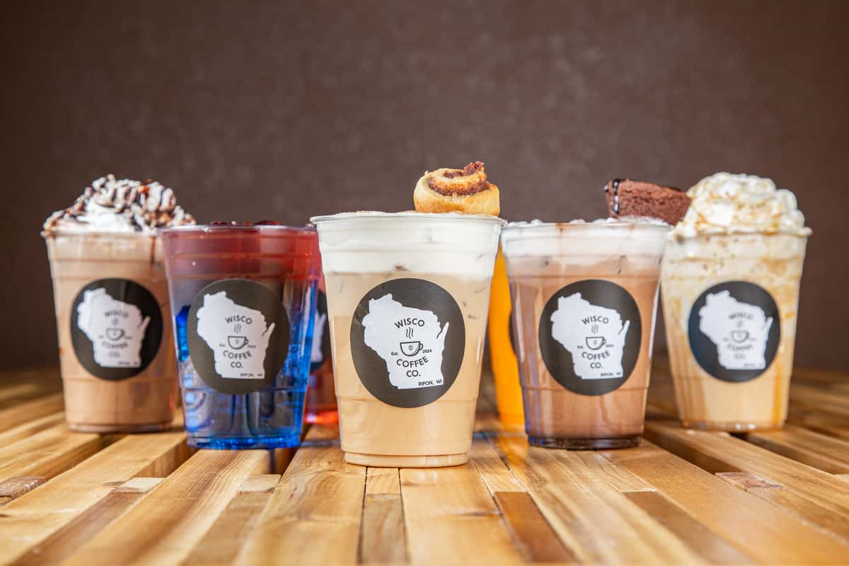 Colorful iced drinks and specialty lattes lineup with whipped cream and toppings at Wisco Coffee Company