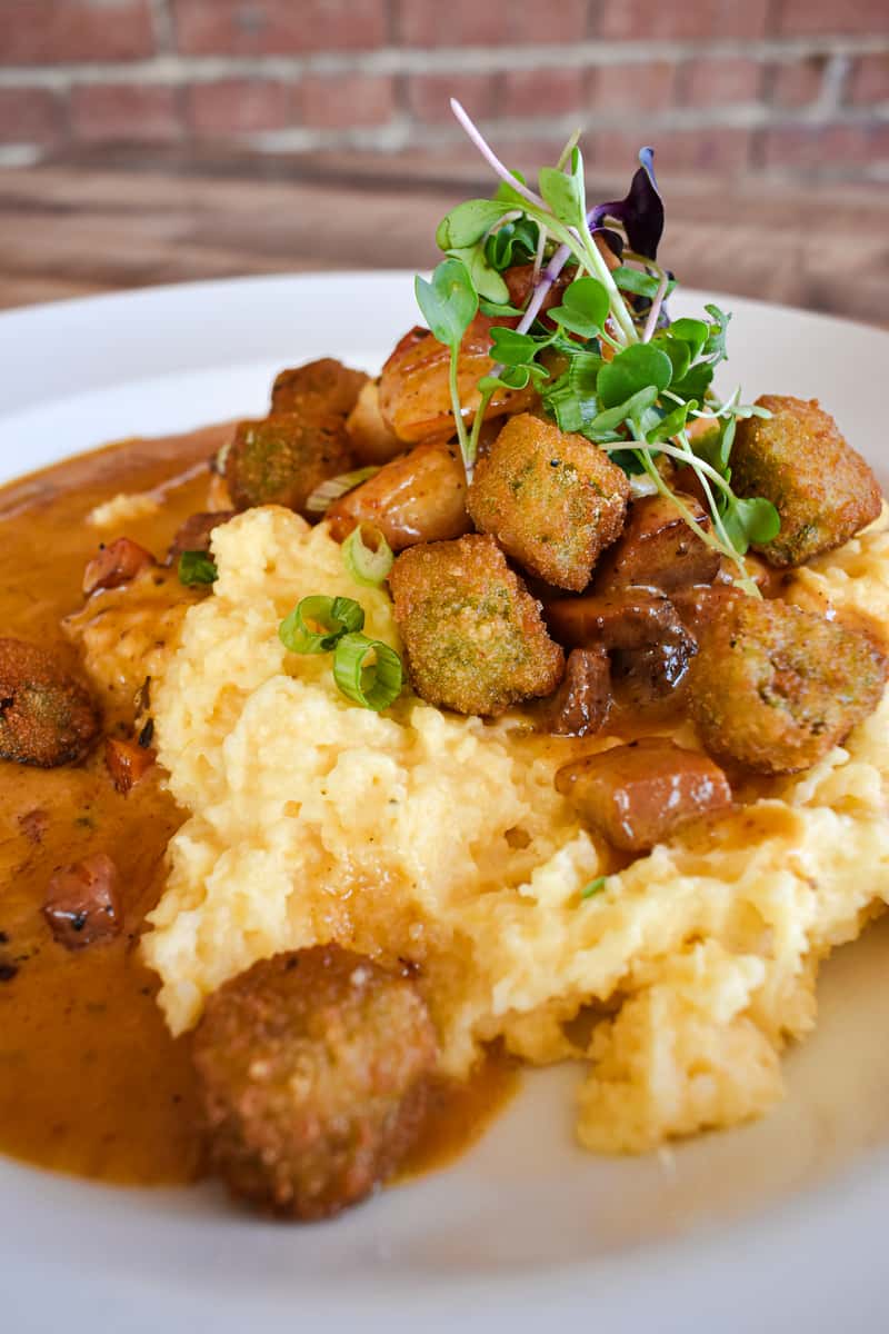 New Orleans-style shrimp sautéed with garlic, Lou Lou dust, butter, fried okra, tasso ham, scallions, red peppers, all served over creamy cheddar grits.