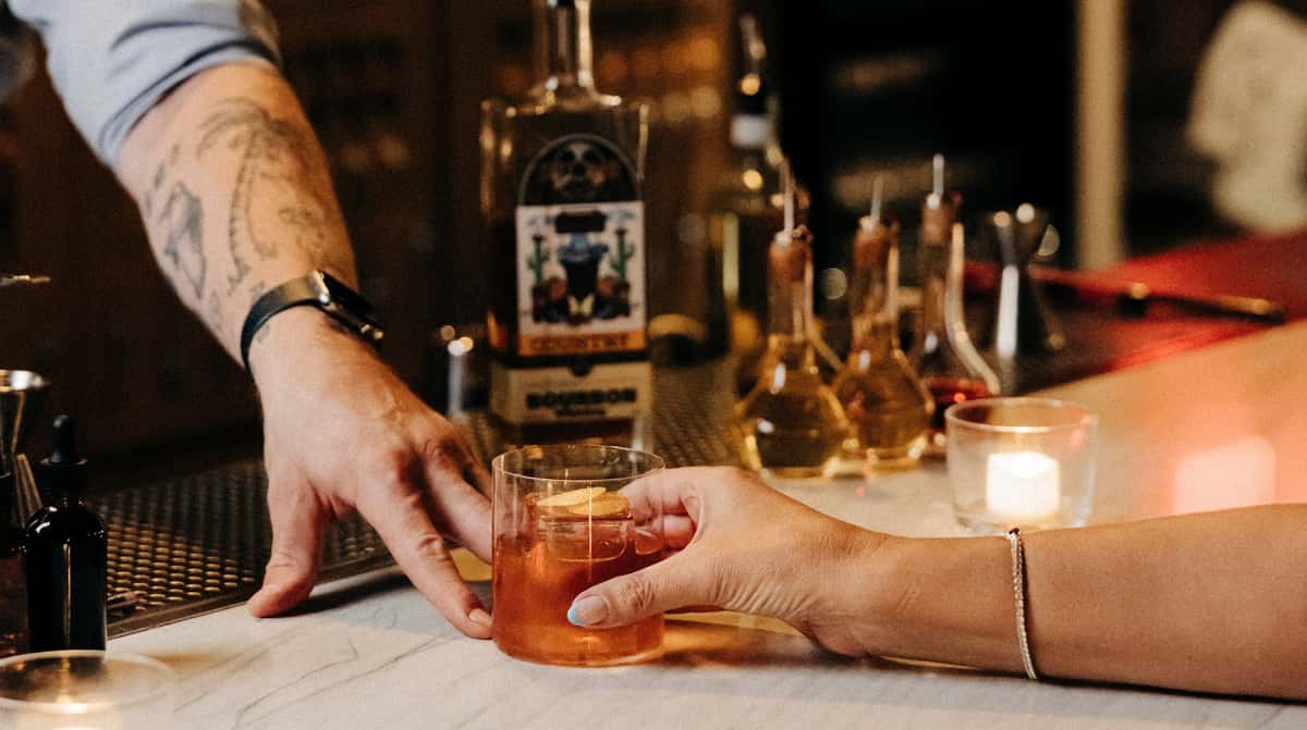 Old Fashioned cocktail being handed to a bar guest at Stone Groove Stillhouse