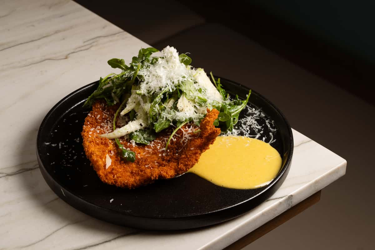Chicken Milanese food entree on a stone table top