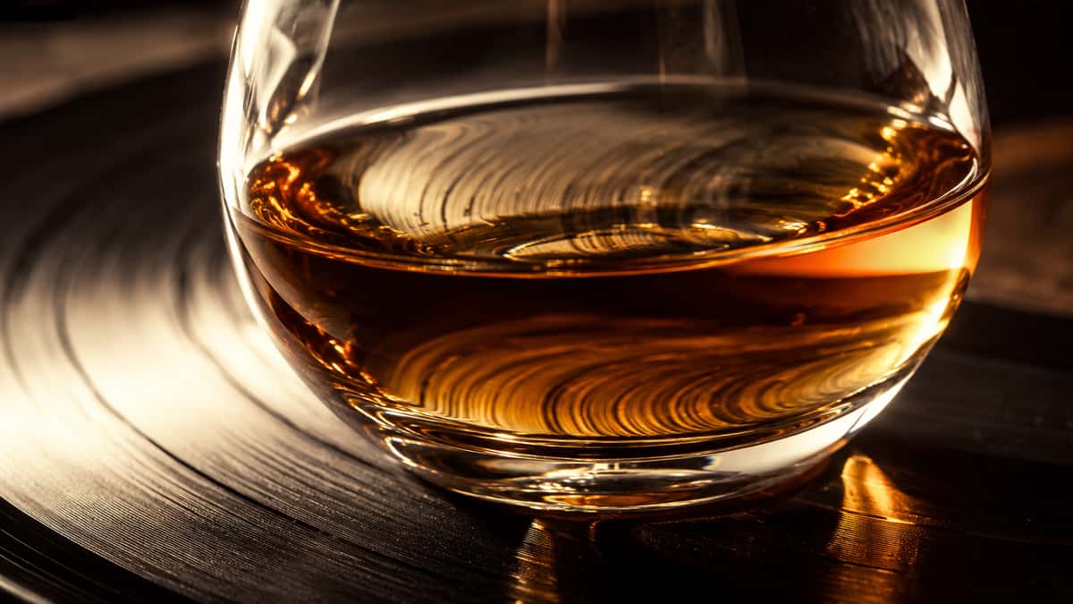 Whiskey in tasting glass sitting on top of a vinyl record