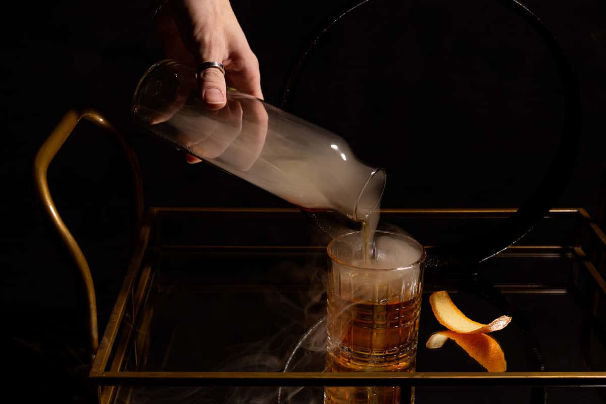 person preparing smoked cocktail.