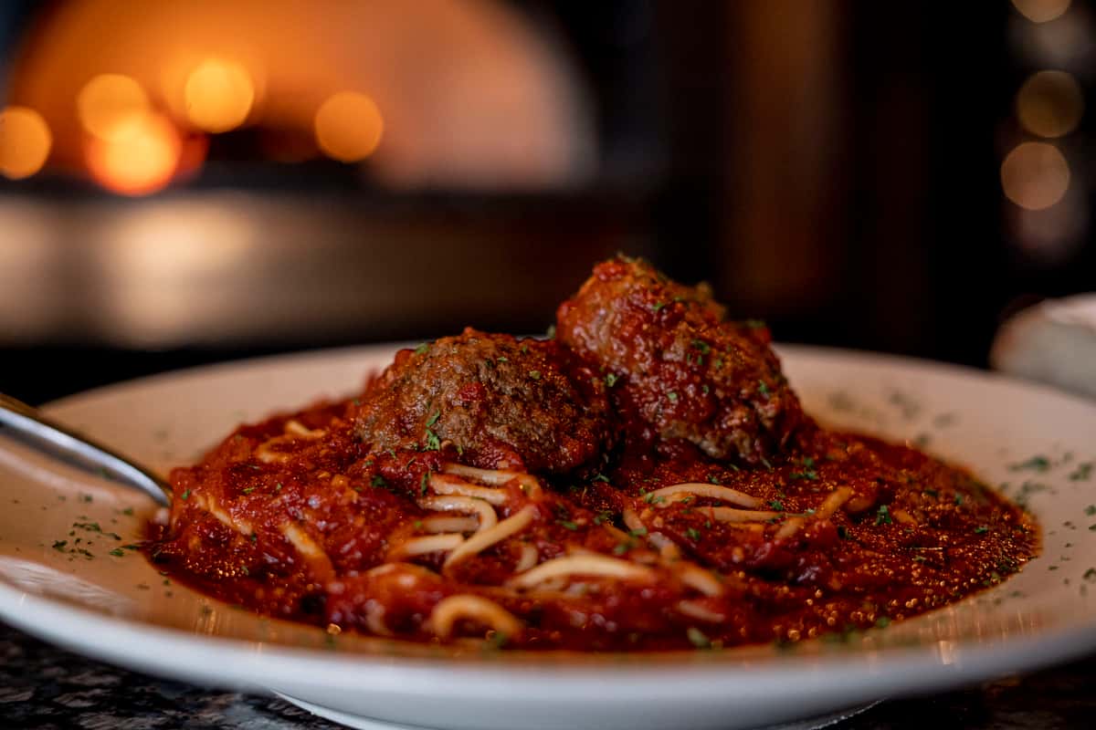 A beautifully plated Italian pasta dish served in rich tomato sauce, topped with a perfectly crisp, golden-brown cutlet and finished with freshly grated parmesan. The warm lighting and elegant presentation create a cozy, upscale dining atmosphere that highlights authentic Italian comfort food with a refined culinary touch.
