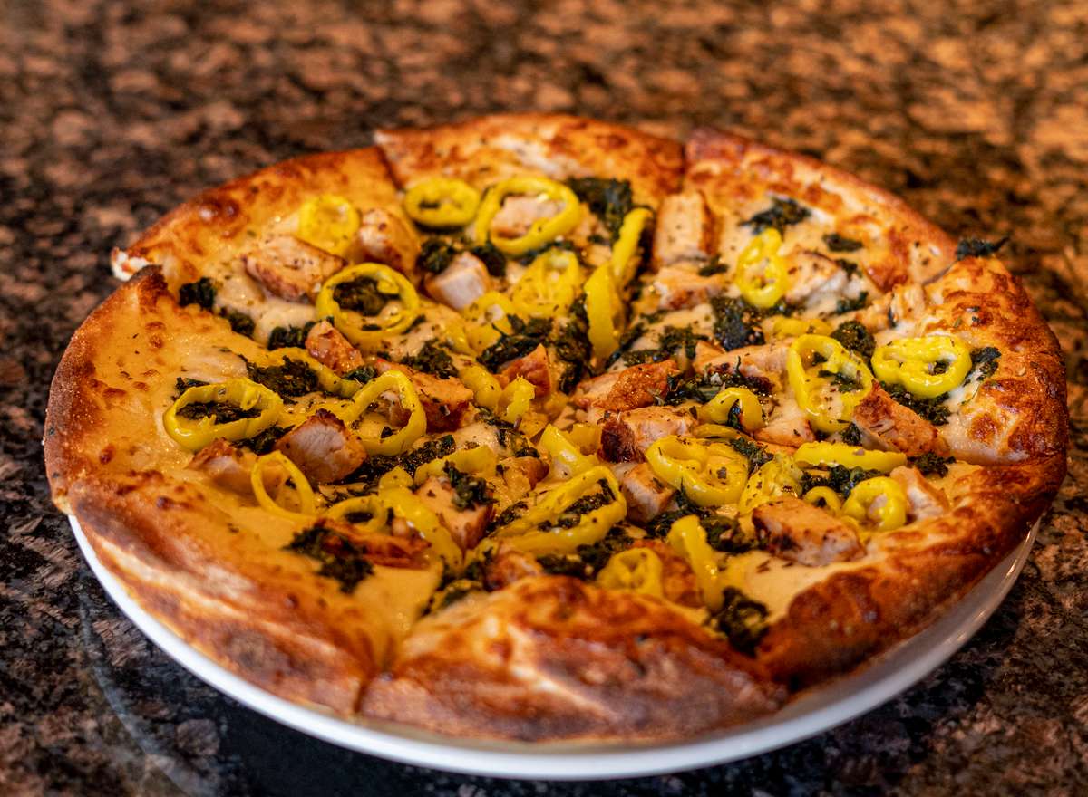 A vibrant gourmet pizza topped with roasted pistachios, melted artisan cheese, and finely crafted Italian ingredients, baked to perfection on a golden, crispy crust. The rich textures and warm presentation capture the essence of elevated Italian cuisine with a modern, luxurious twist.