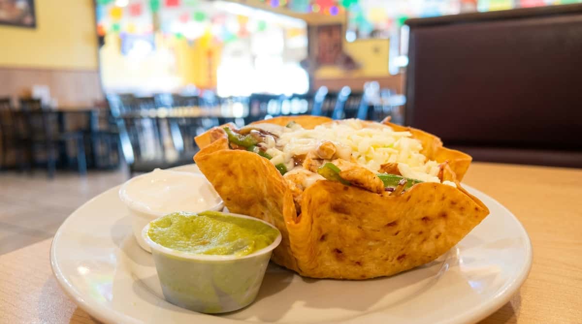 Crispy taco salad filled with seasoned beef, fresh lettuce, tomatoes, shredded cheese, and guacamole at Maya Mexican Restaurant in Homewood and Alabaster, Alabama.